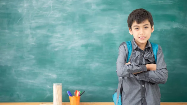 学生男孩指着教室里的黑板 — 图库照片