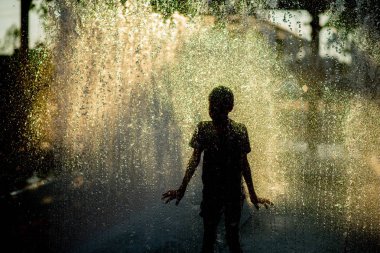 Küçük çocuk su oynarken bez ve şemsiye altında çeşme damlaları