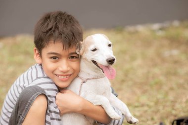 Küçük çocuk parkta köpeği jack russell sarılmak