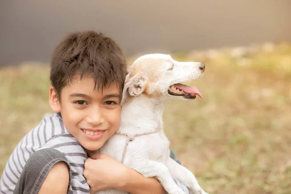 小男孩在公园里拥抱他的狗杰克 鲁塞尔 — 图库照片