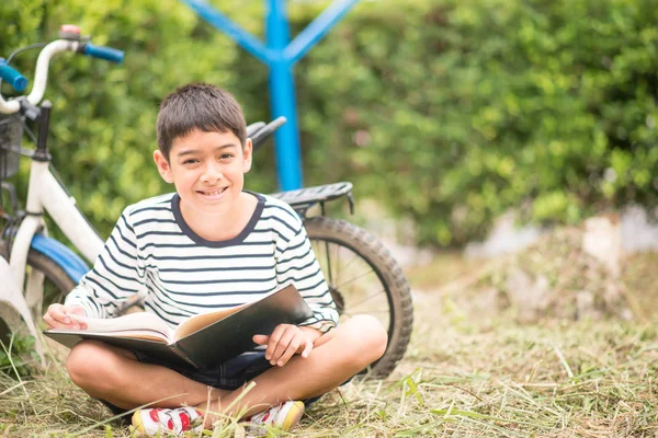 Ένα Μικρό Αγόρι Που Διαβάζει Βιβλίο Και Κάθεται Ποδήλατο Στο — Φωτογραφία Αρχείου