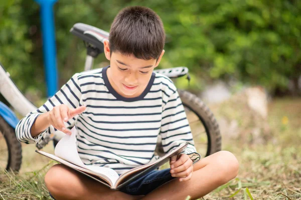 Маленький Мальчик Читает Книгу Сидя Велосипедом Парке — стоковое фото