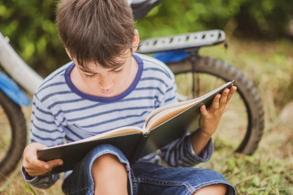 Parkta Bisikletle Oturan Küçük Çocuk Kitap Okuyor — Stok fotoğraf