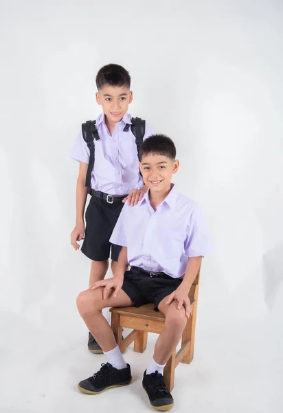 小亚洲兄弟姐妹男孩在学生制服一起摆姿势在白色背景 — 图库照片