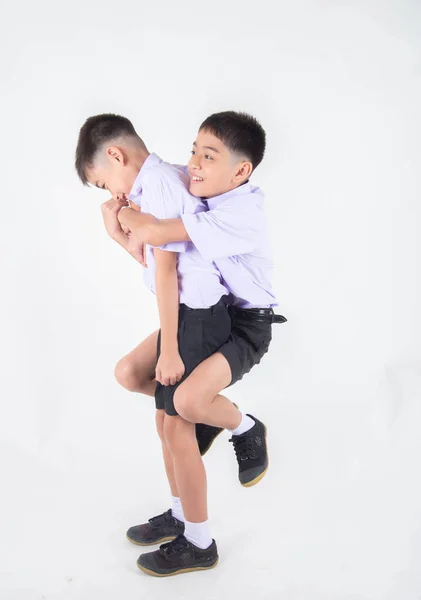 小亚洲兄弟姐妹男孩在学生制服一起摆姿势在白色背景 — 图库照片