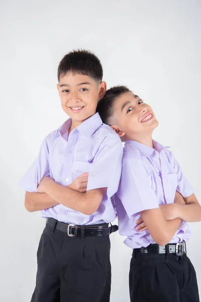 小亚洲兄弟姐妹男孩在学生制服一起摆姿势在白色背景 图库照片