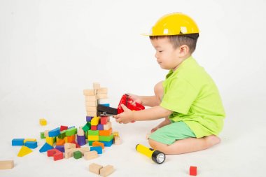 Küçük Asyalı yürümeye başlayan çocuk ahşap bloklar oynarken kask mühendisi giymek