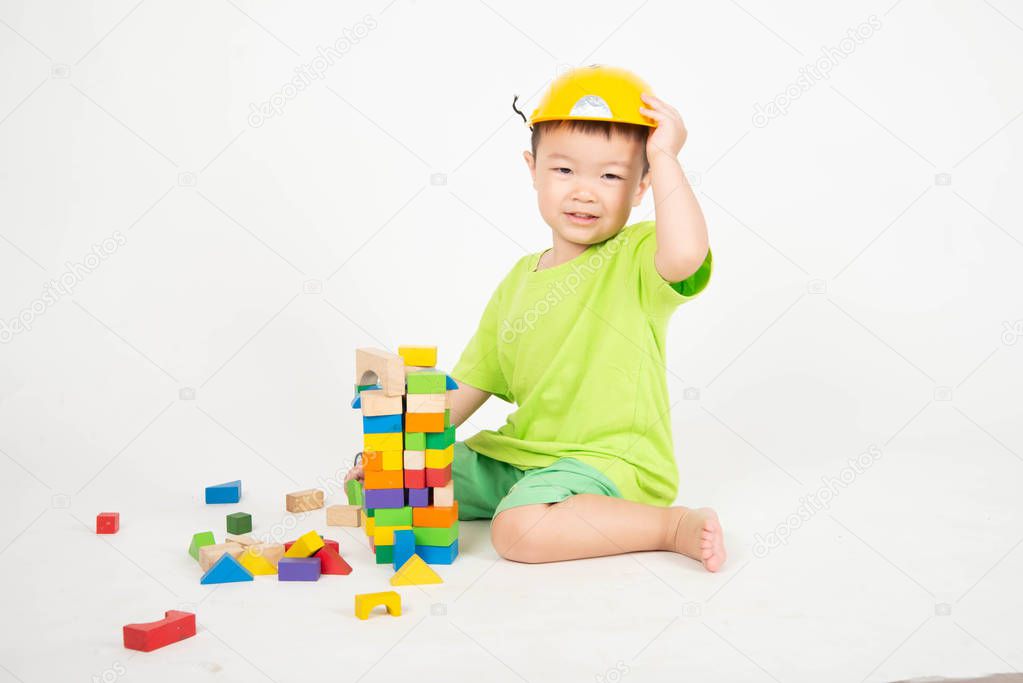 Little Asian toddler boy playing wood blocks wear helmet engineer