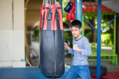 Little Asian boy learn and train boxing with punch bag
