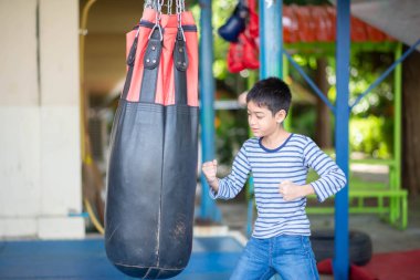 Little Asian boy learn and train boxing with punch bag