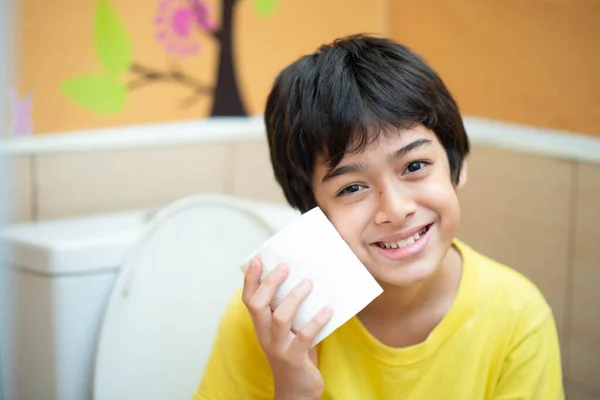 小男孩在厕所里用干净的纸巾 免版税图库图片