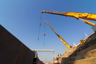 Kuru rıhtım üzerinde çalışan iki kamyon vinçler gemi gövde par kaldırıyor