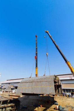 Kuru rıhtım üzerinde çalışan iki kamyon vinçler gemi gövde par kaldırıyor