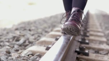 Mor çizmeli genç kadın tren yolunda yürüyor. Yavaş çekim. Seyahat, tehlike, yaşam tarzı.