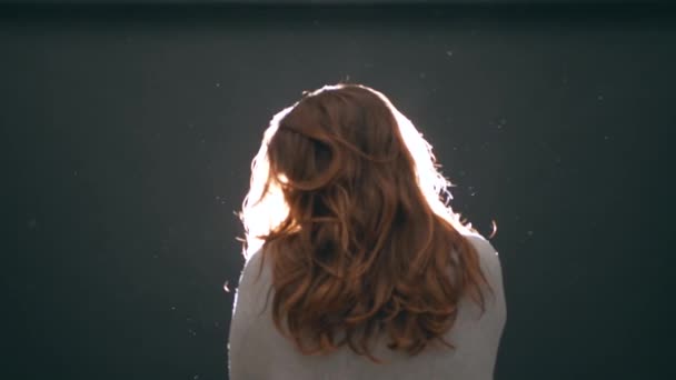 머리를 여성은 섬세하게 머리를 흔든다 초점을 실루엣 백그라운드에서 아름다운 입자가 — 비디오