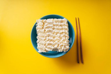 Üst Manzara - Bir kâse içinde hazır şehriye ve sarı arka plan üzerinde çubuk.