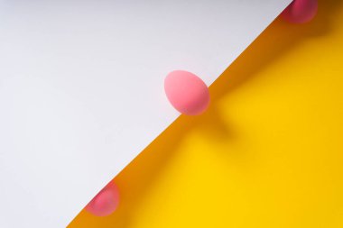 Üst Manzara - Beyaz ve sarı arkaplan üzerine pembe yumurtalar.