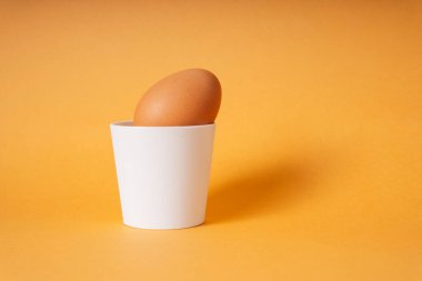 Haşlanmış organik tavuk yumurtası seramik bardakta ya da tutacağında.