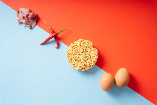肉豚肉 スパイスチリ インスタントラーメン 青と赤の背景に卵とトム ユーム成分 — ストック写真