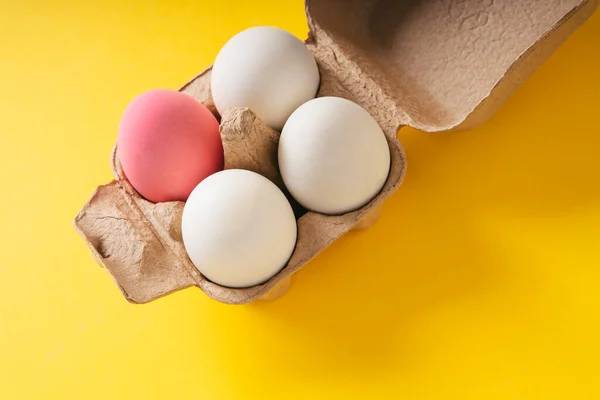 Top View One Pink Egg Three White Egg Box Yellow — Stock Photo, Image