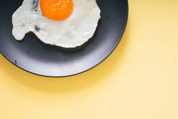 Świeże Jajko Smażone Czarnym Talerzu Żółtym Tle — Zdjęcie stockowe