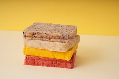 Sarı zemin üzerinde dilimlenmiş renkli ekmek yığını.