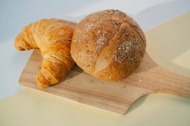 Tam buğday ekmeği ve ahşap yastıkta altın haç..