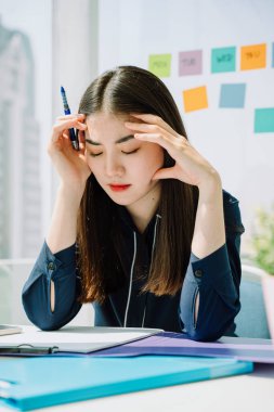 Sokak güzeli Asyalı genç Taylandlı uzun siyah saçlı kadın ofis masasında çalıştıktan sonra başı ağrıdı. Mutsuz İş Kadını.