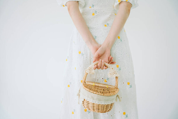 Crop image of beautiful woman in white ress holding picnic basket isolate over white background.