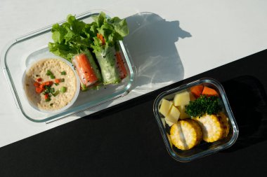 Yumurta buharı soslu ve ızgara sebzeli taze böreğin en üst görüntüsünde mısır ve patates havucu siyah ve beyaz desenli arka planda bir kutu içerir..