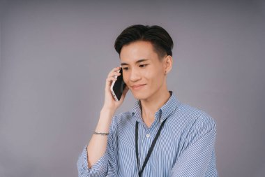 Mavi yakalı yakışıklı iş adamı telefonda konuşuyordu. Gri arkaplan üzerinde izole.