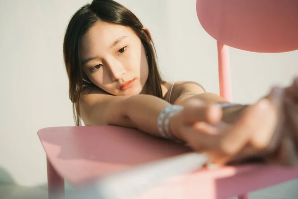 Güzel Taylandlı kadın beyaz odadaki pembe sandalyeye ölçü bandıyla el bağla..