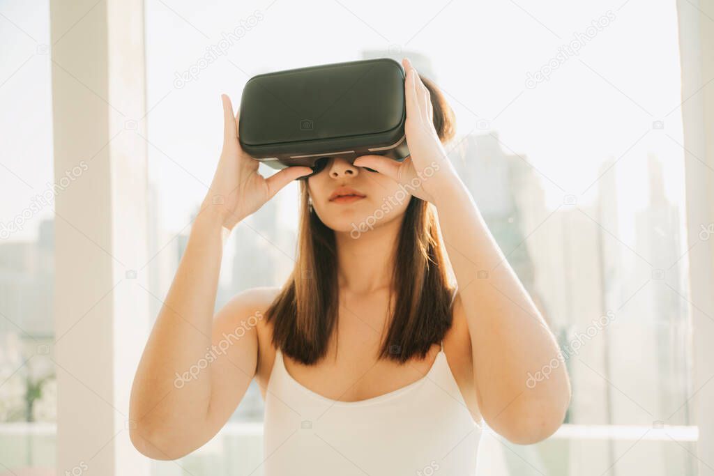 Close up beautiful asian thai woman wearing VR headset, playing virtual reality game. Technology in gaming industry. Over skyscraper background.