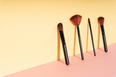 Sarı duvara dayanan kozmetik fırçalar. Boşluğu kopyala.
