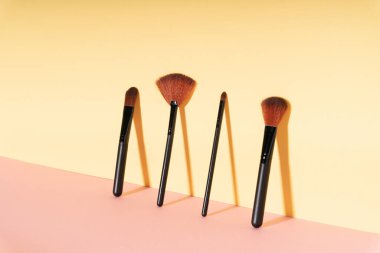 Sarı duvara dayanan kozmetik fırçalar. Boşluğu kopyala.