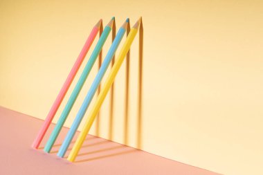 Parlak sarı duvara yaslanmış renkli pastel kalem..