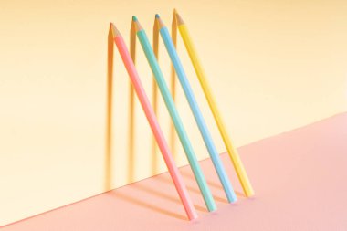 Parlak sarı duvara yaslanmış renkli pastel kalem..