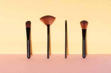 Sarı duvara dayanan kozmetik fırçalar. Boşluğu kopyala.