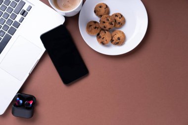 Üst Manzara - Kahve fincanı, kurabiye, akıllı telefon, kredi kartı ve dizüstü bilgisayarı olan ofis masası işyeri.