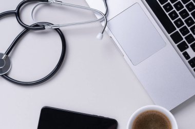 Üst görünüm - Doktor stetoskop, laptop, kitap ve gözlüklü çalışma masası.