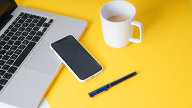 Arka plan - Modern ofiste çalışan sarı iş adamı ve bir fincan kahve, kalem, akıllı telefon, dizüstü bilgisayar.