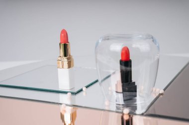 Altın rengi kırmızı ve pembe ruj ve ayna masasında siyah sürgü. Siyah olan cam kaseyle kaplanmış. Kozmetik konteynır. Lüks ruj..