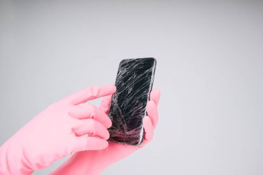 Covid-19 her yerde. Pembe eldivenli doktorun eli akıllı telefondan plastik kapağı açıyor..