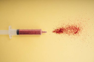 Şırıngadan akan aşı sarı arka planda izole edilmiş..