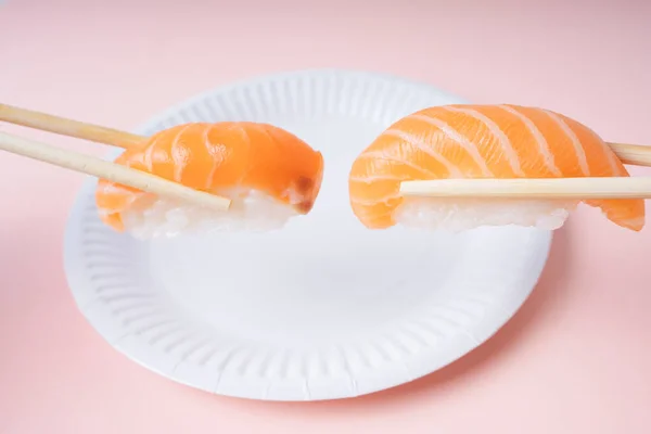 白盘上新鲜的鲑鱼寿司 用筷子抹粉红背景 — 图库照片