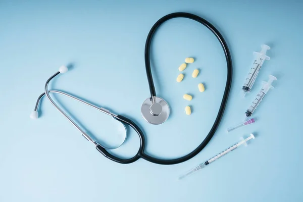 医生背景 听诊器和带蓝色背景注射器的药丸 — 图库照片