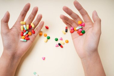 Elinde renkli ilaç hapları tutan adamın elleri beyaz sarı arka planda izole edilir..