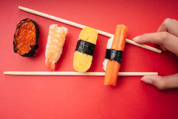 俯瞰全景 用筷子在红色背景上烤鲑鱼虾卵卷蟹棒 — 图库照片