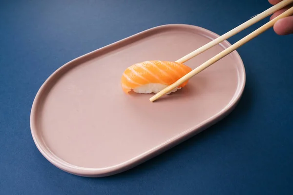 吃新鲜的鲑鱼寿司 用筷子盖着蓝色背景 — 图库照片