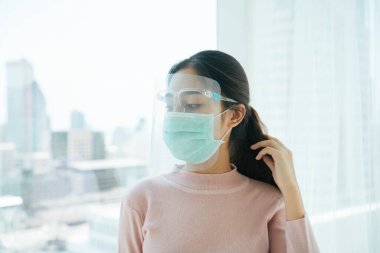 Yeni normal moda - Asyalı Taylandlı uzun siyah saçlı kadın yüz koruyucusu ve maskesi takıyor.